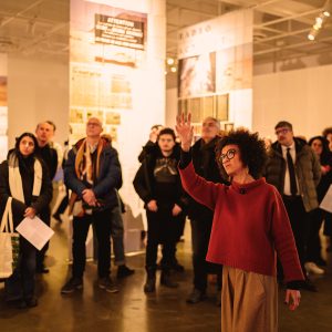 Photographie d'une visite guidée de Samia Henni commissaire de l'exposition "Toxicité coloniale" présentée au Centre de design de l'UQAM du 19 févr. au 12 avr. 2026. Crédit photo : Benoit Rousseau